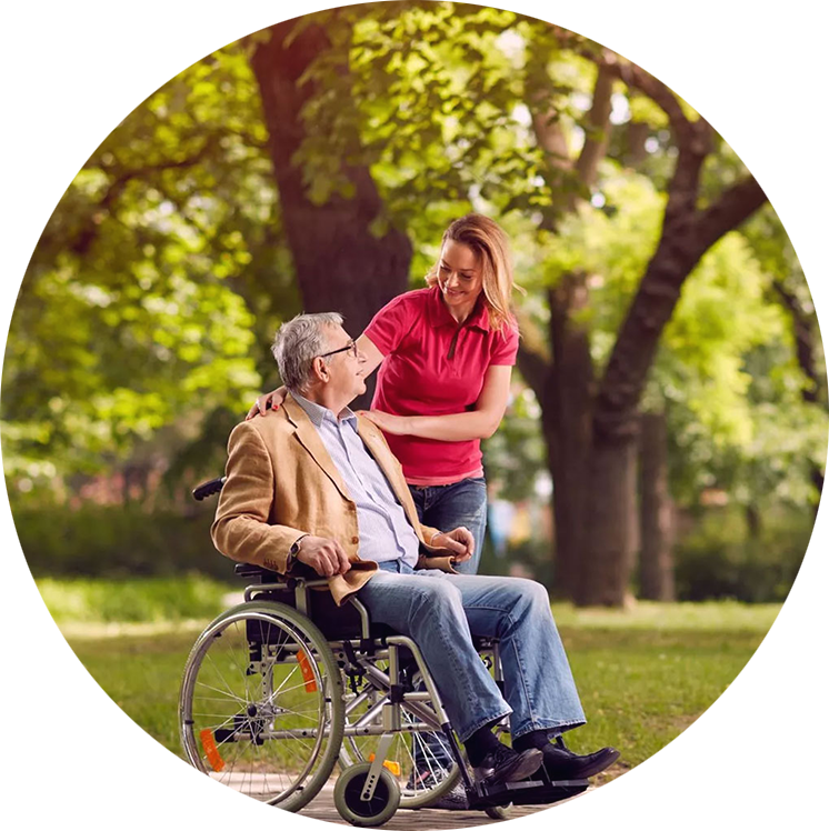 An occupational therapist out for a walk in a park with a client in a wheelchair